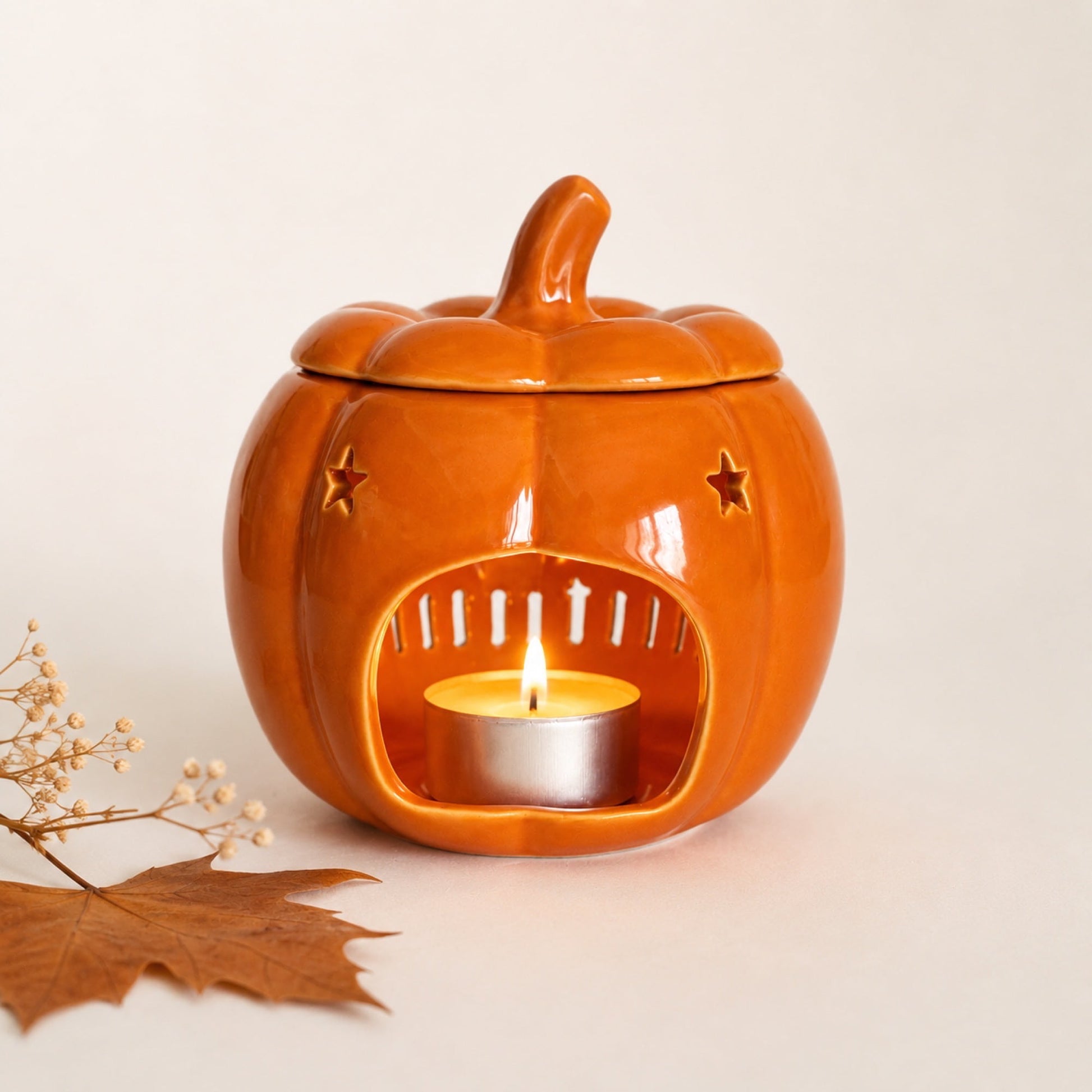 Quemador de cera con forma de calabaza y vela de té encendida para wax melts de Ayre