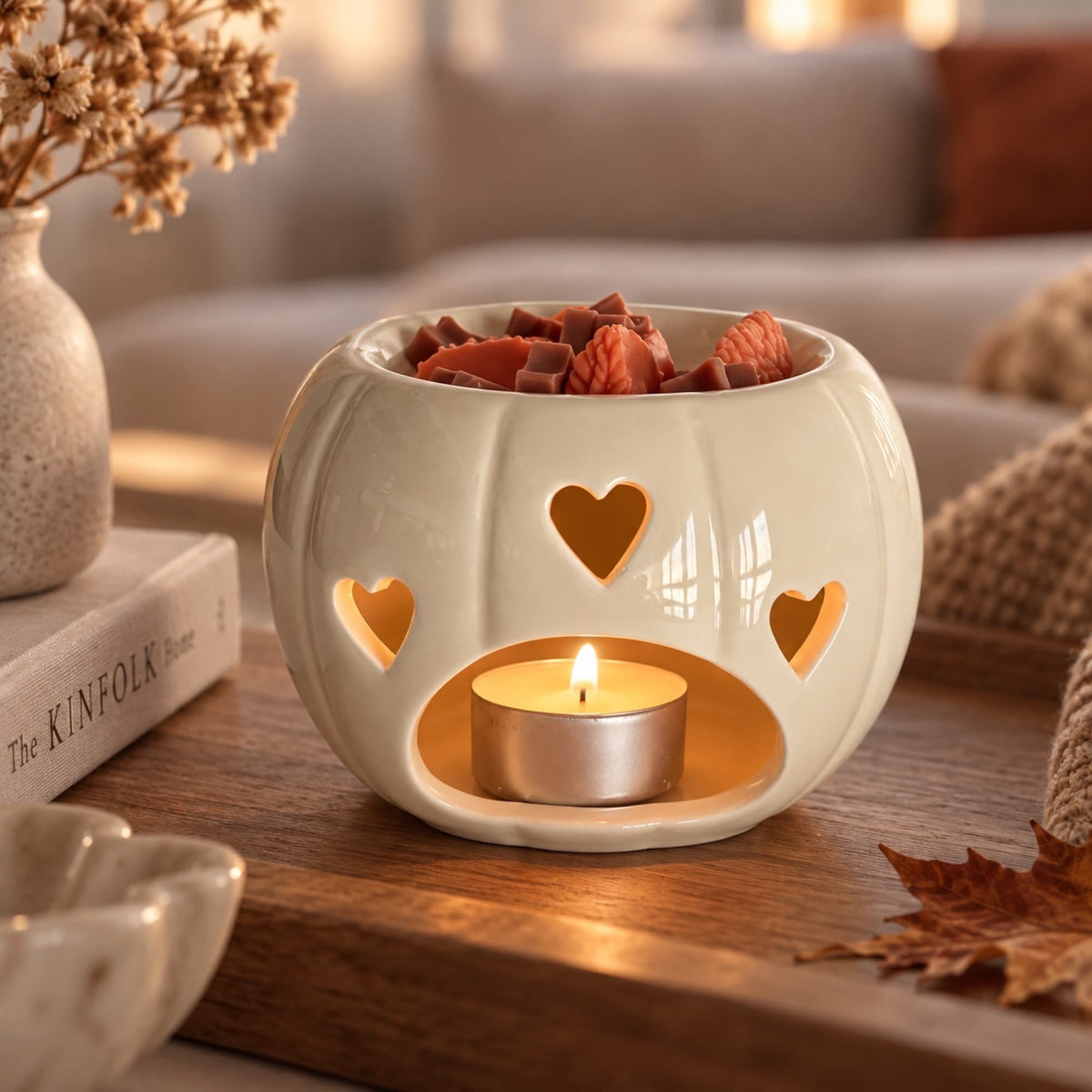 Quemador de wax melts con forma de calabaza encendido con vela de té en ambiente otoñal