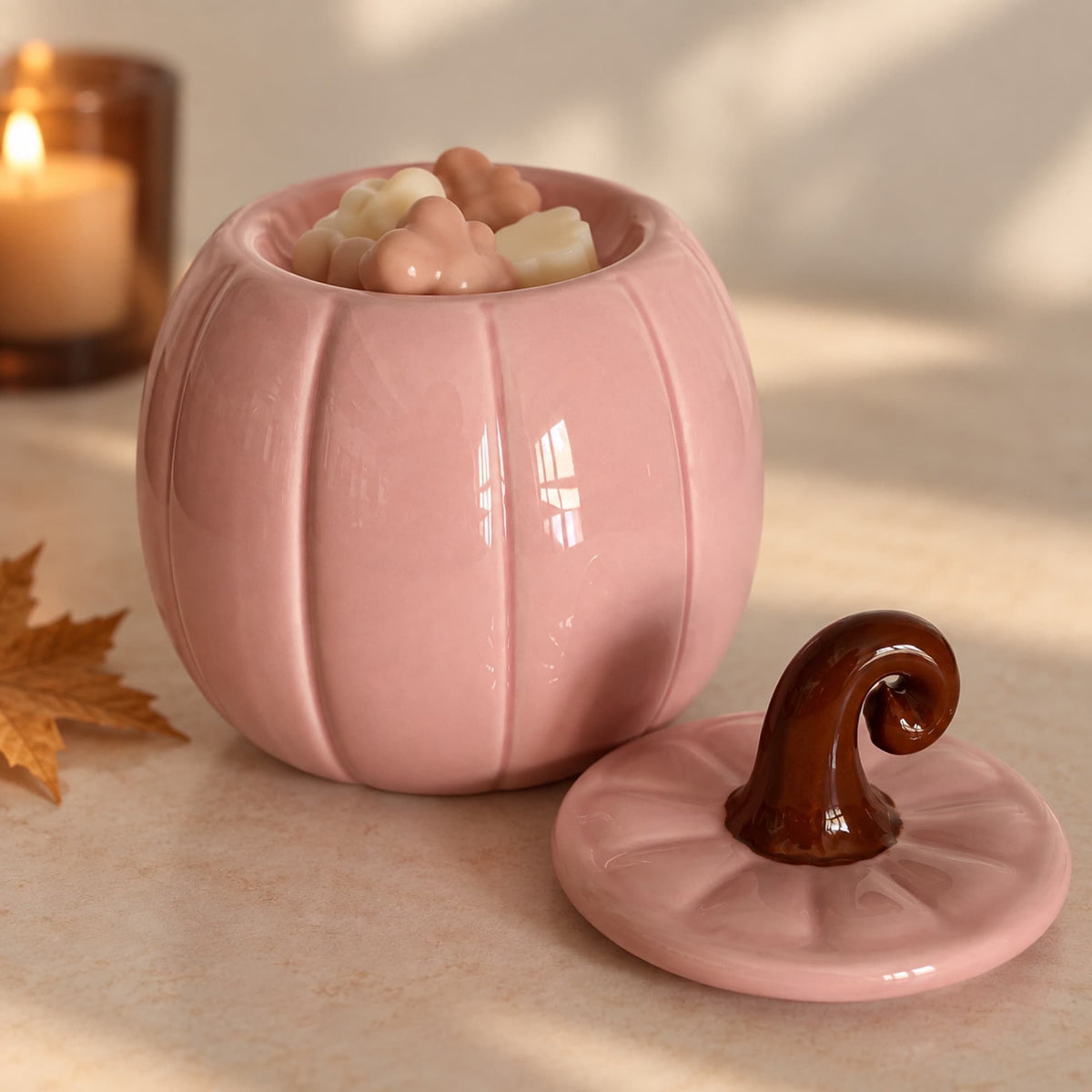 Quemador de cera rosa con forma de calabaza abierto con wax melts en su interior