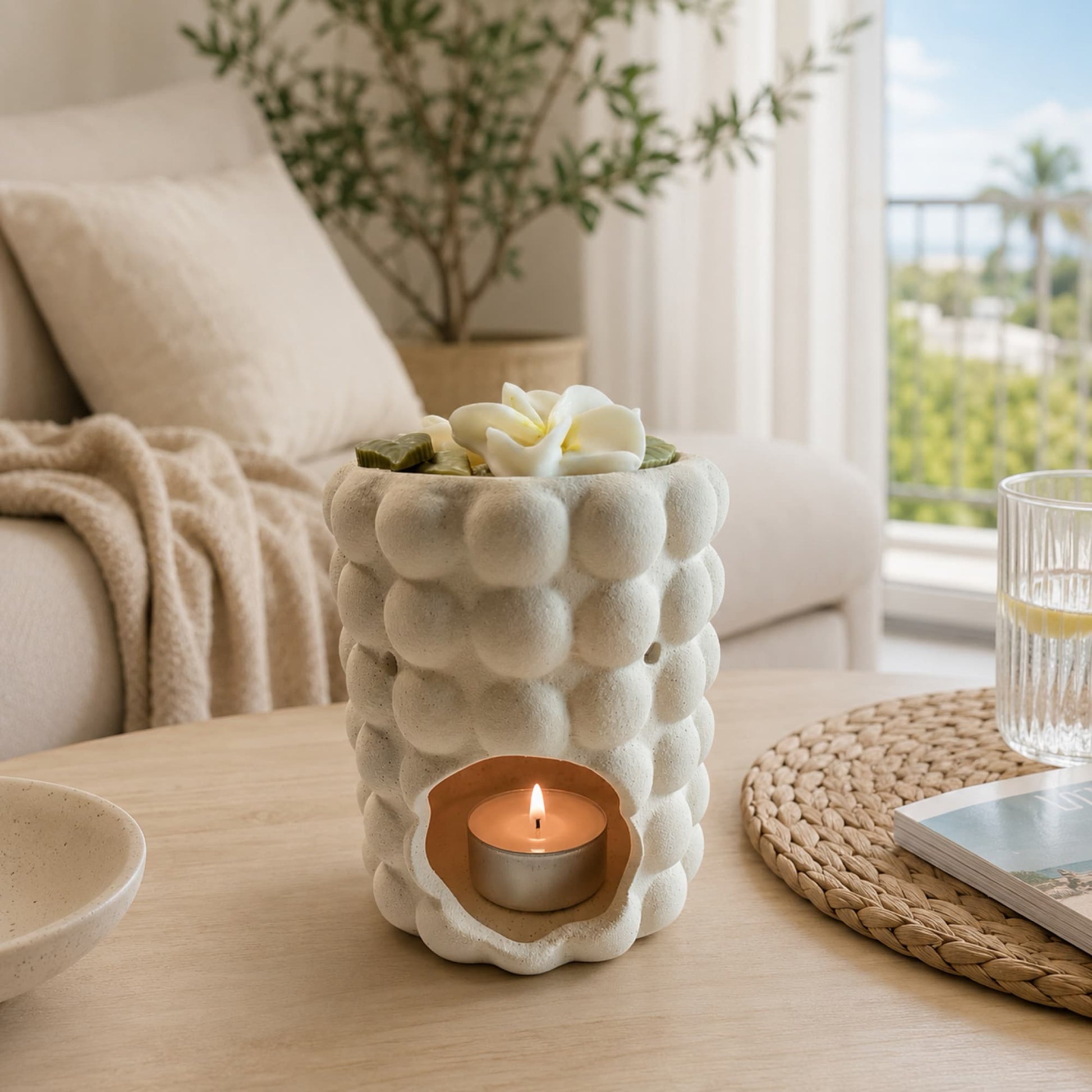 Quemador de wax melts Monoï de Ayre encendido con flores de tiaré aromáticas.