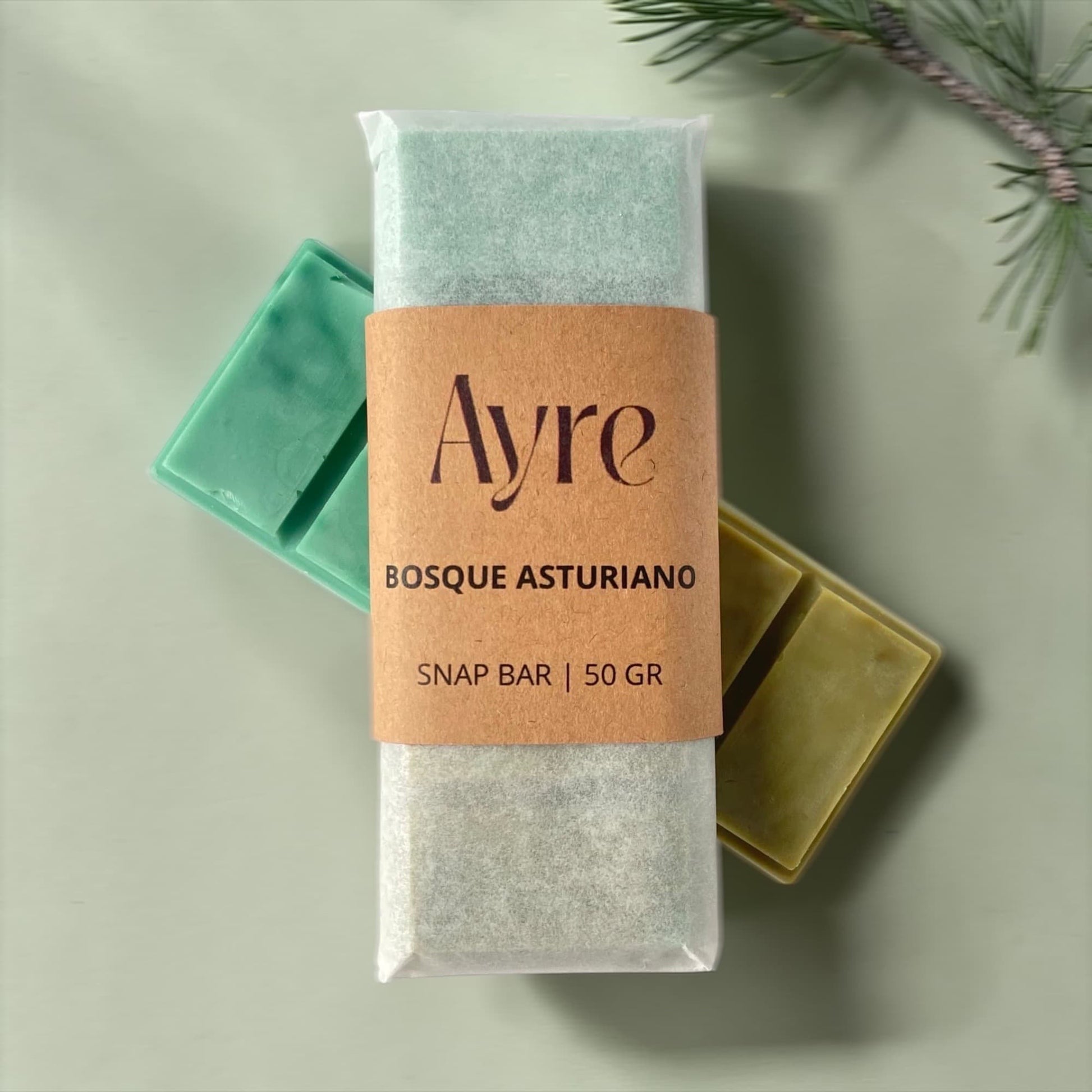 Snap bar de cera de soja Ayre con aroma bosque asturiano, ambientador aromático con tonos verdes y rama de pino sobre fondo suave