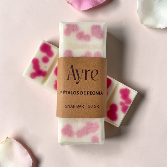 Snap bar de cera de soja Ayre con aroma a pétalos de peonía, ambientador aromático con diseño en tonos rosados sobre fondo suave