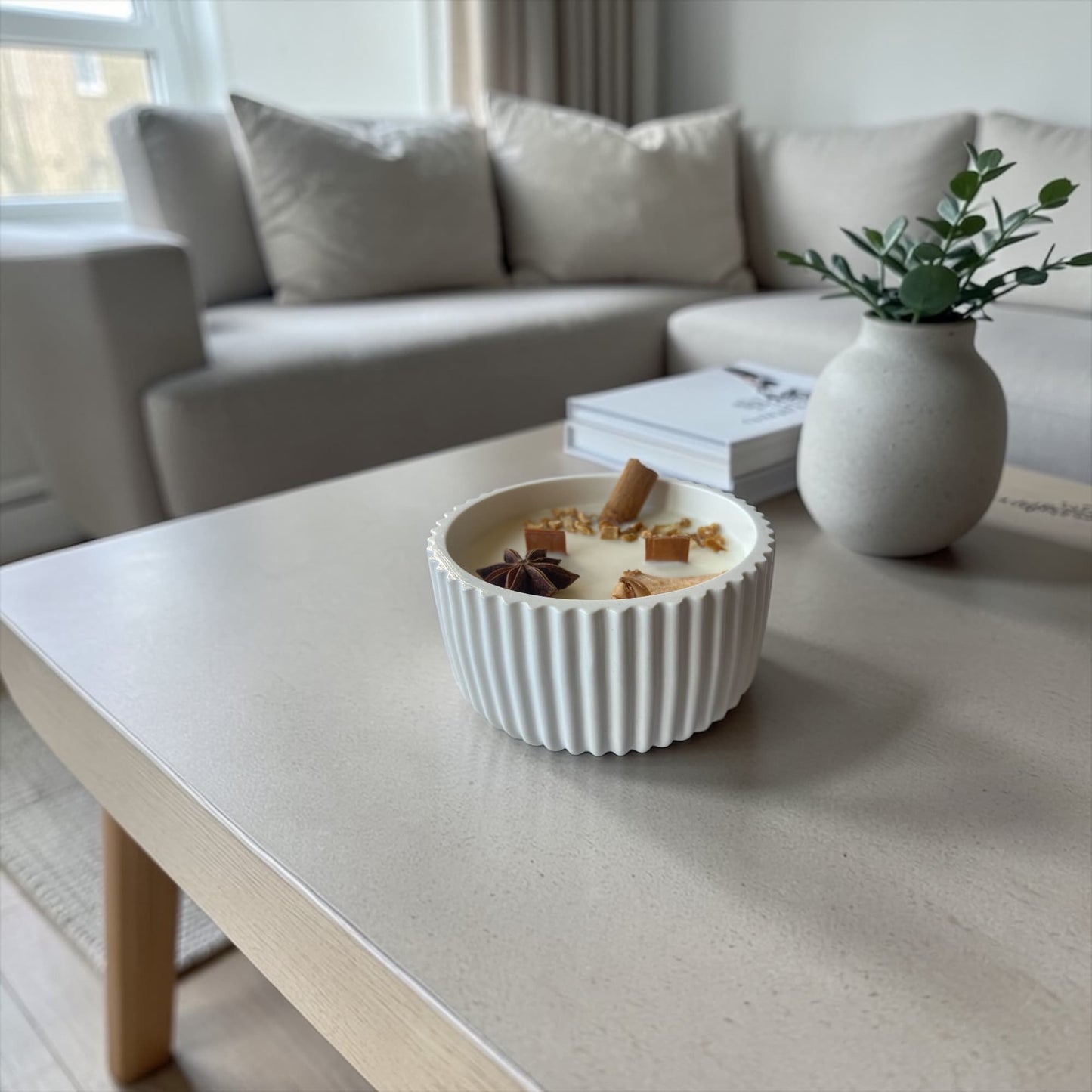 vela aromática de soja manzana y canela decorativa sobre mesa de salón