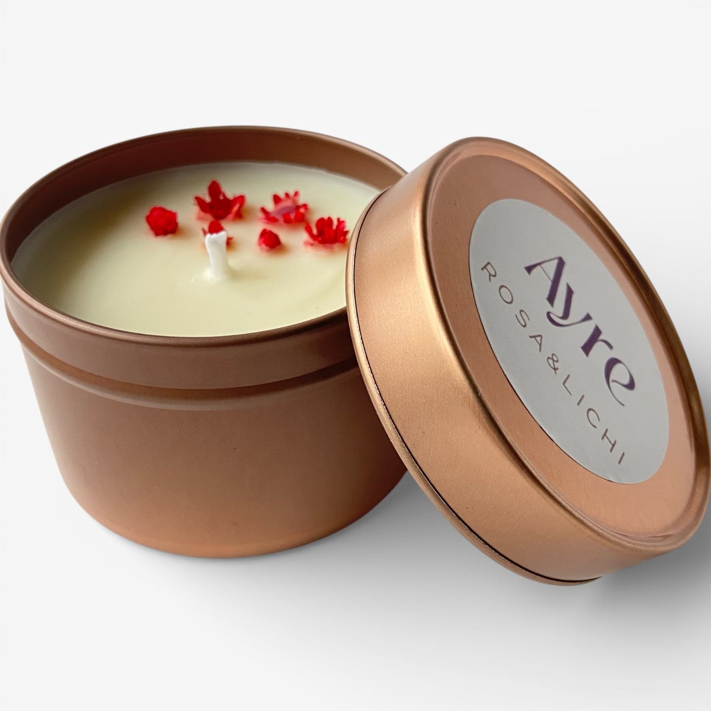 Vela aromática de soja Rosa y Lichi Ayre abierta en lata metálica.